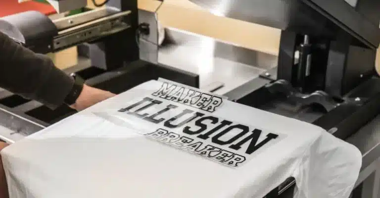 A man applying the printed design on a white shirt with heat presser.