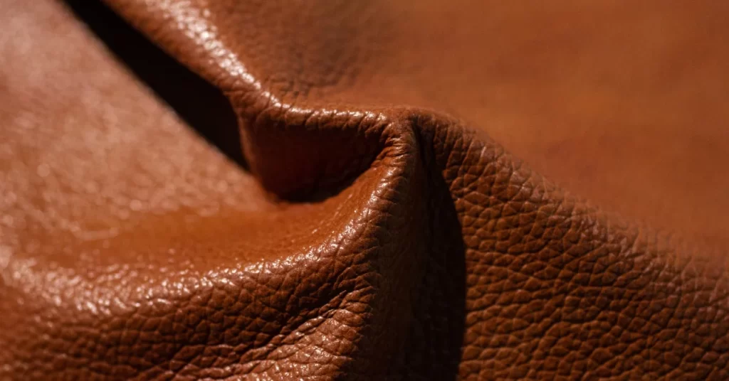 Close-up view of a textured faux leather surface in a rich brown color, showing the fine details and creases that mimic genuine leather.