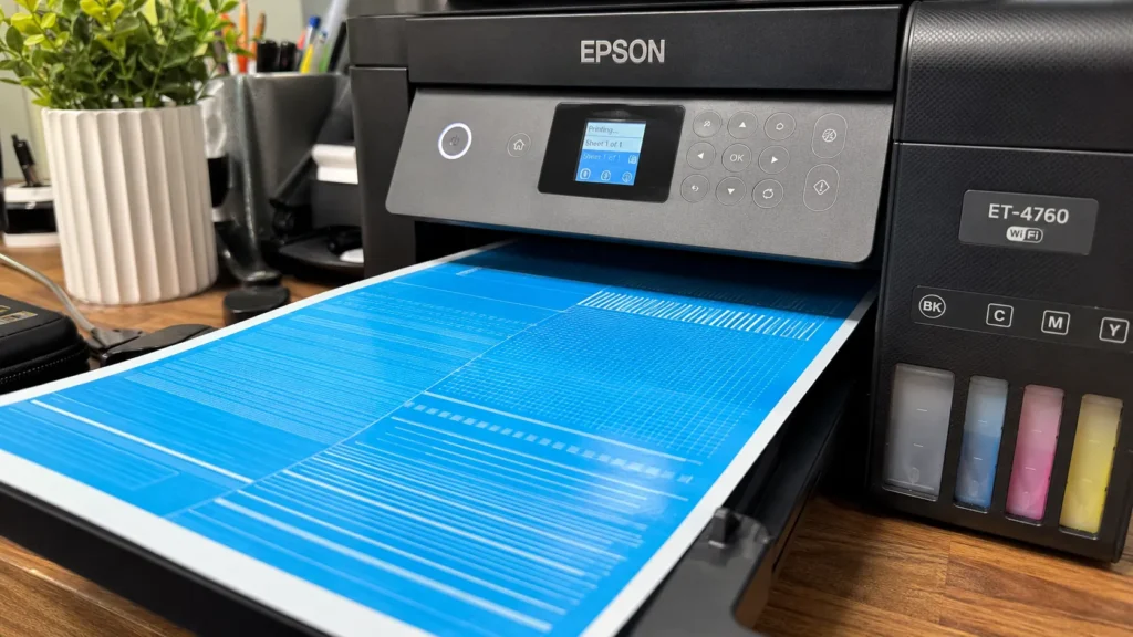 A close-up photo of an Epson EcoTank printer printing a full-page cyan purge sheet.